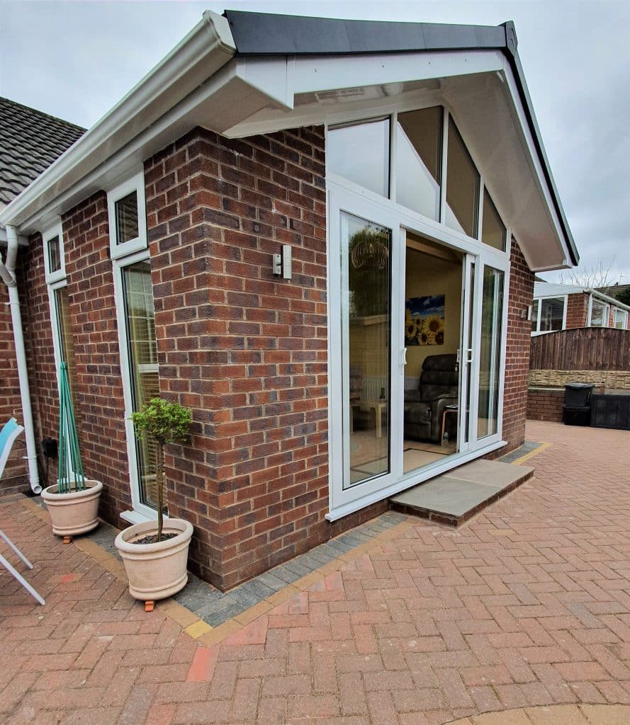 Brick-built garden room extension in Clock Face, St Helens, with white bi-folding doors and a pitched roof.