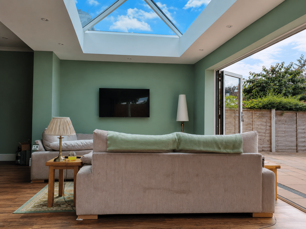 Bright orangery interior in St Helens with a large glazed roof lantern, open garden doors and a modern living