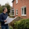 Homeowner with building plans by house side