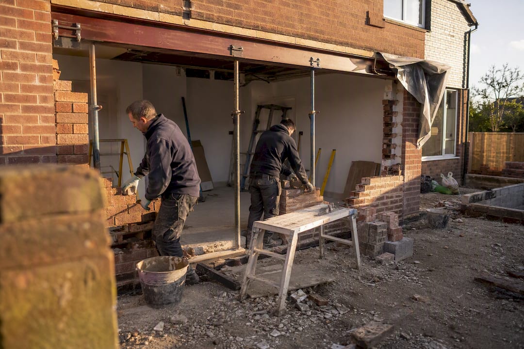 Bricklayers widening wall opening for patio door